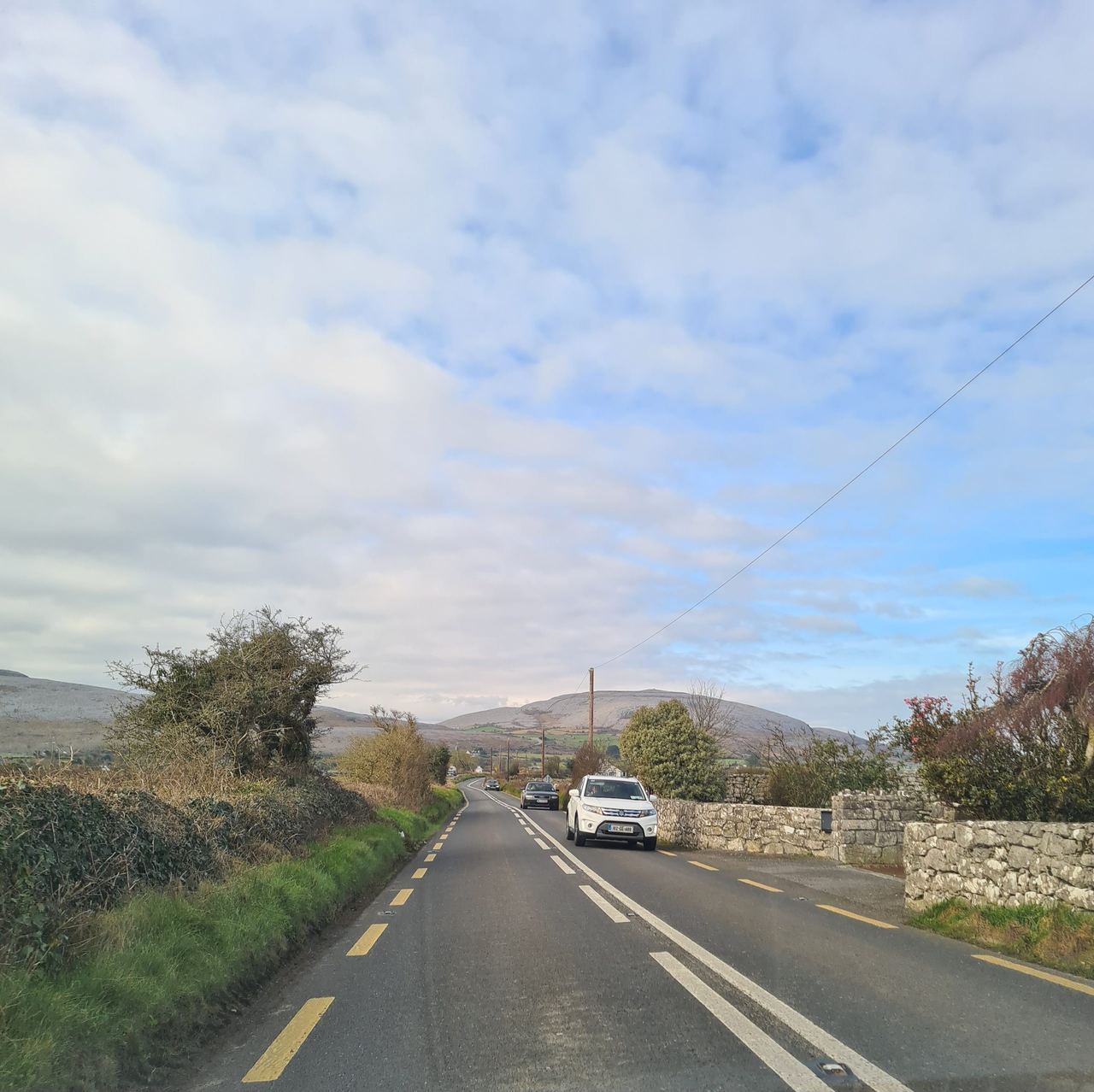 Rural road with left lane traffic cars driving toward us on the right side of the road