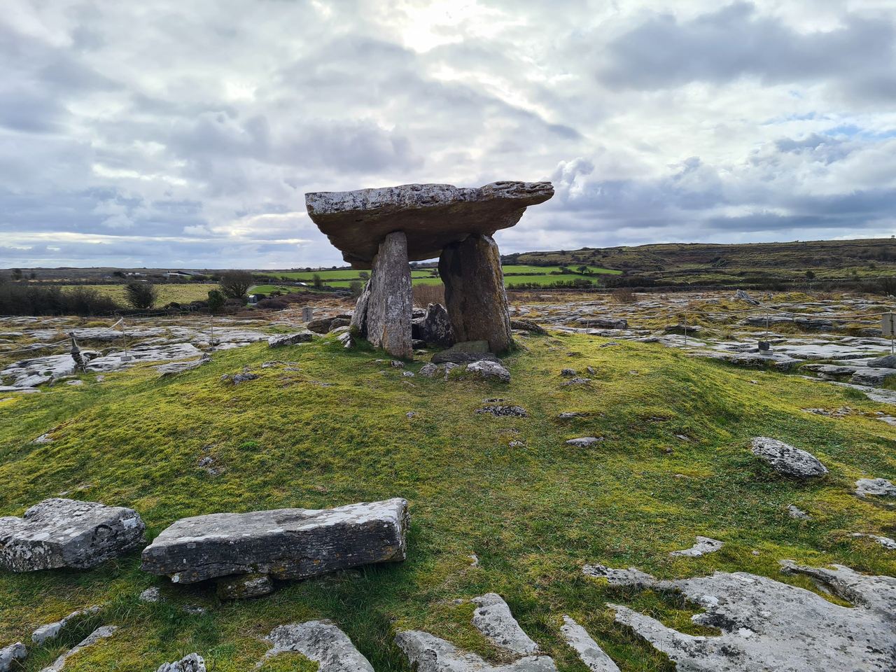 Stack of ancient stone slabs forming a gate in the middle of a grass covered limestone field on a cloudy day