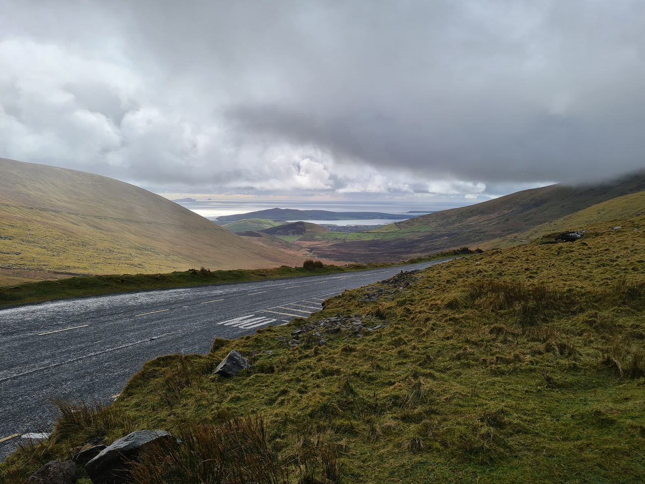 View from a mountain pass with yellowish grass, mountain road on a cloudy day