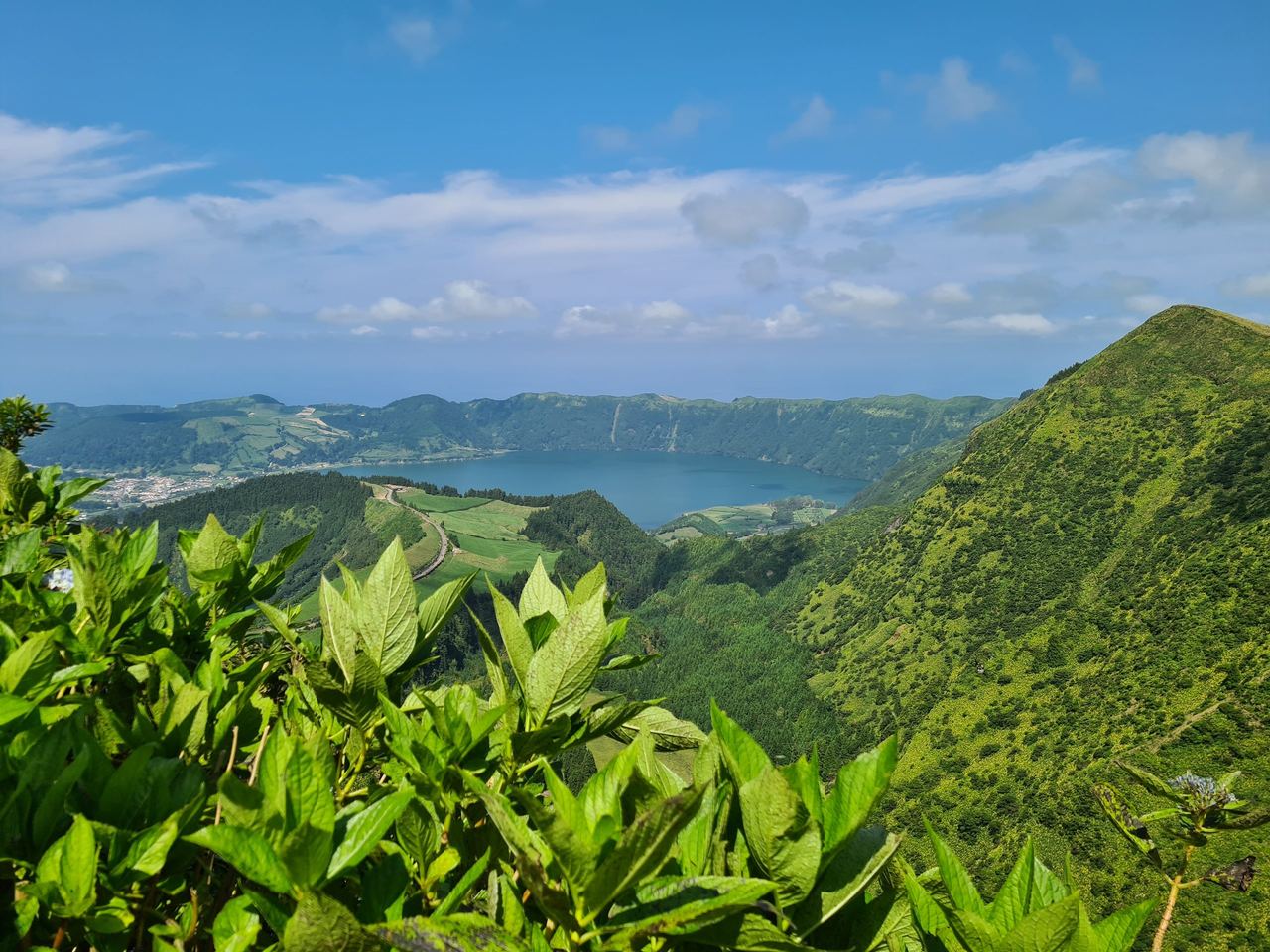 View of a crater lake in the Azores, with the ocean in the background
