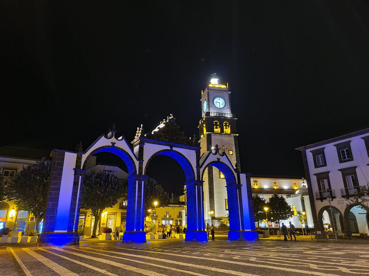 Town square in the night with illuminated arch and clock tower in the Azores