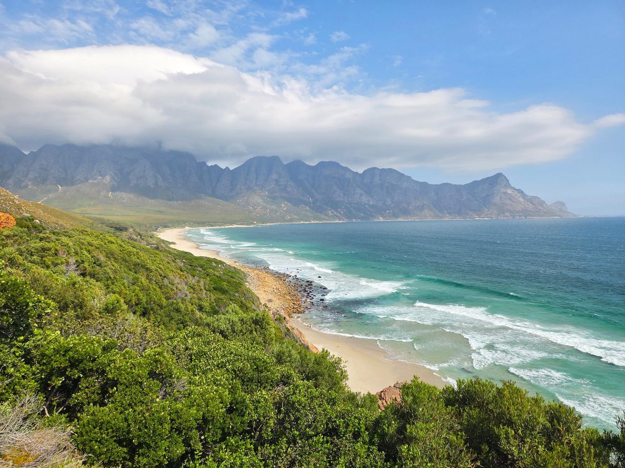 Huge bay in South Africa, pictured from above, sandy shore, partially cloud covered mountain range in the background