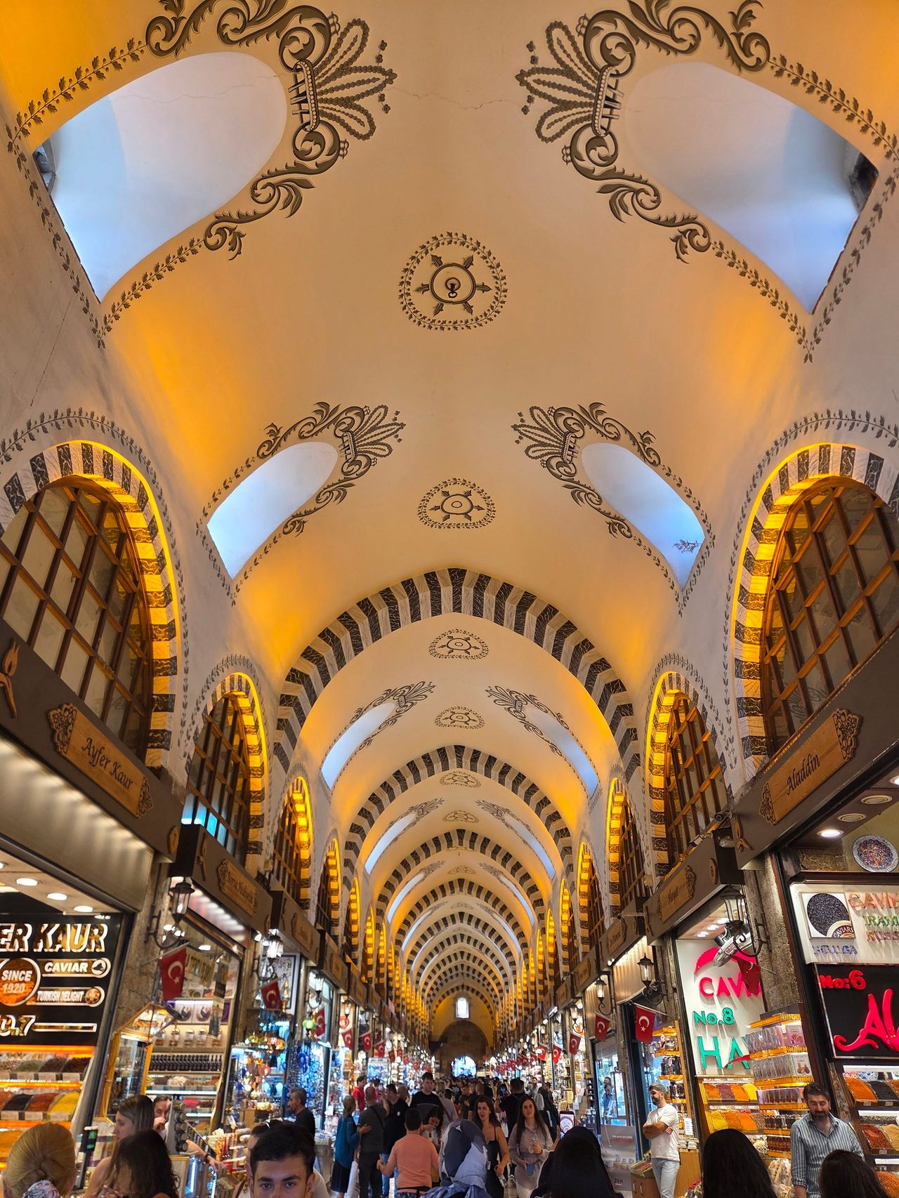 Inside of Egyptian Bazaar; ornate cream vaults with dark floral patterns and glowing amber arches