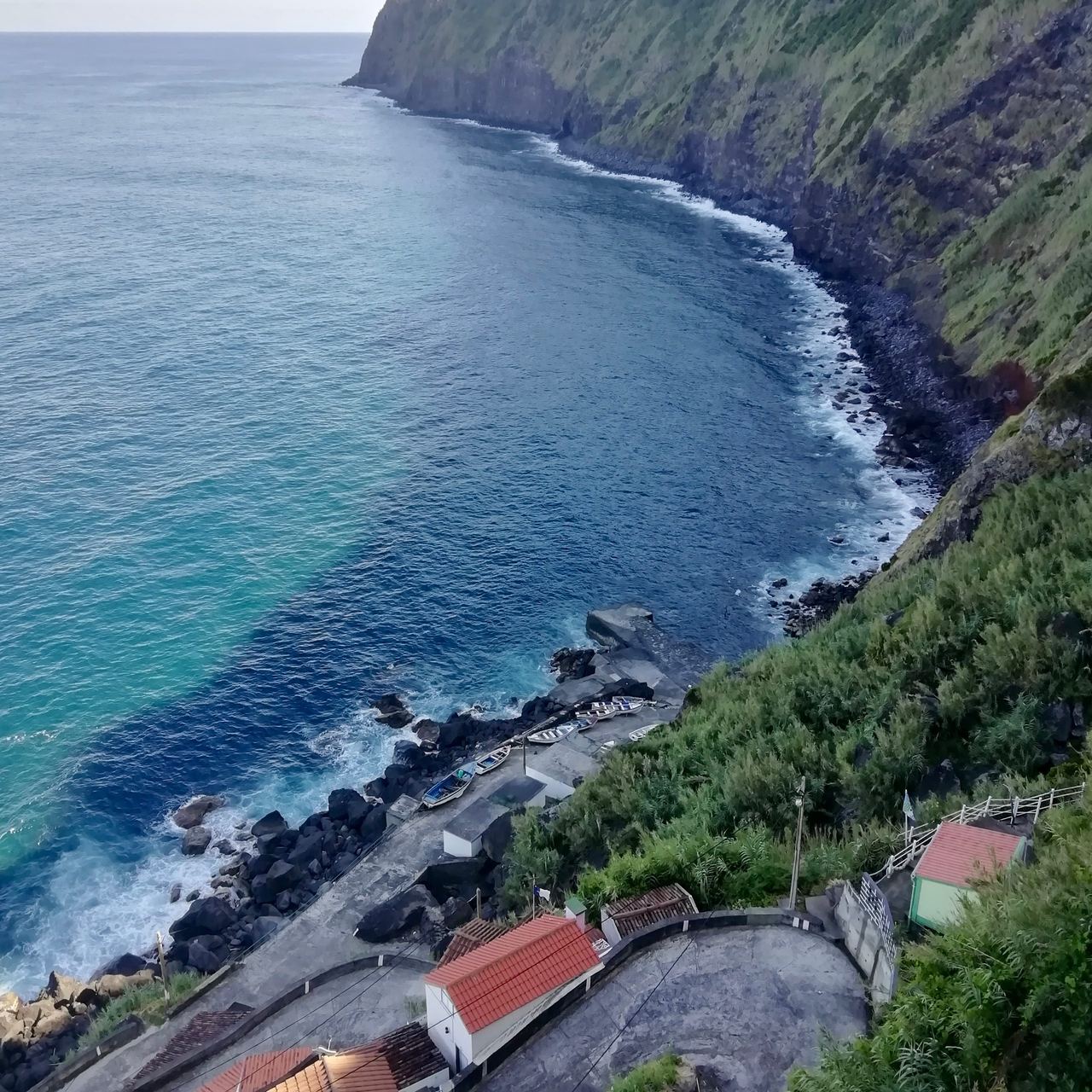 Mountainous shore on the ocean with a steep road and a few fishing houses