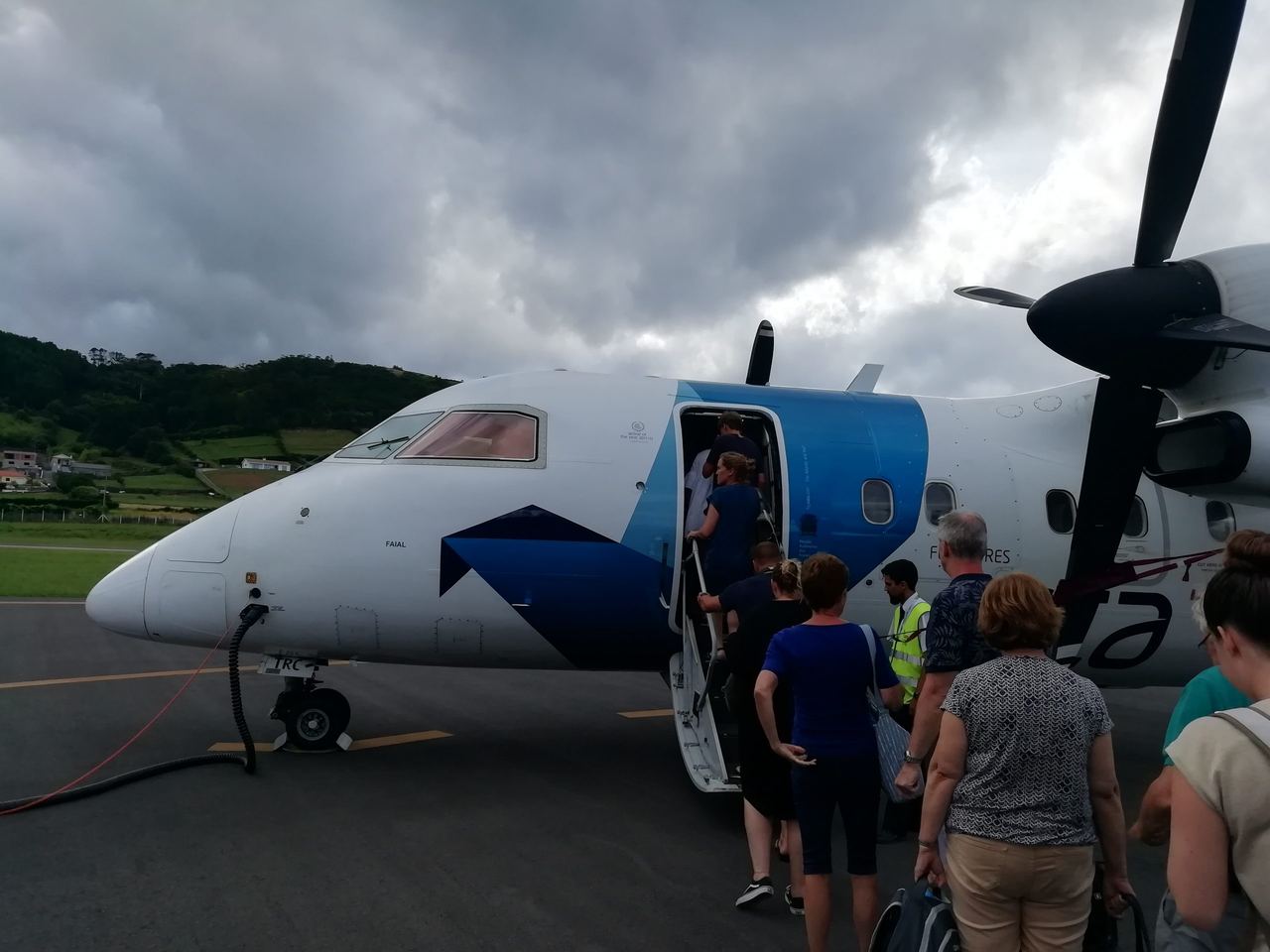 Passangers boarding a small commercial aircraft on a cloudy day