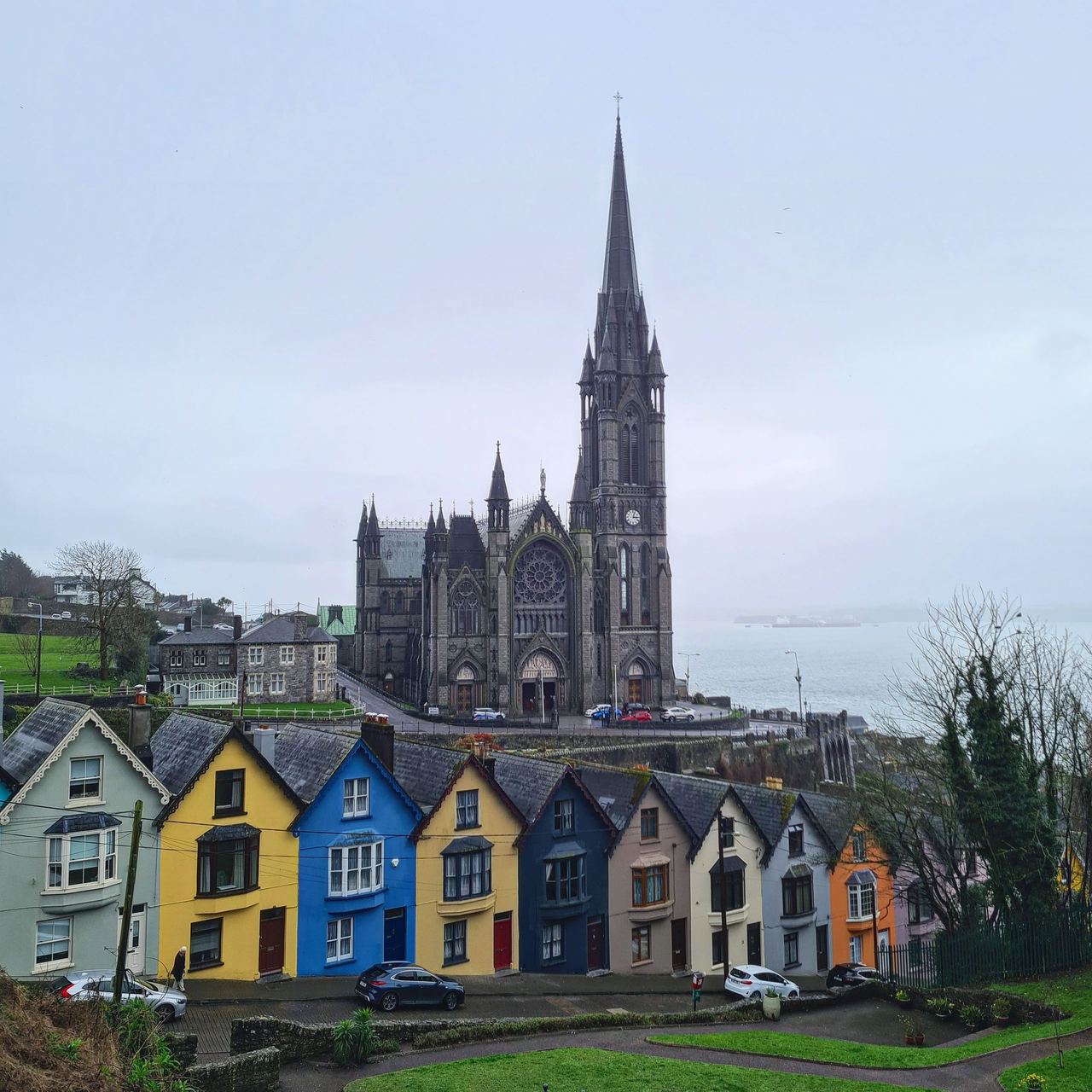 Huge gothic church next to the sea with colourful terraced houses in the foreground